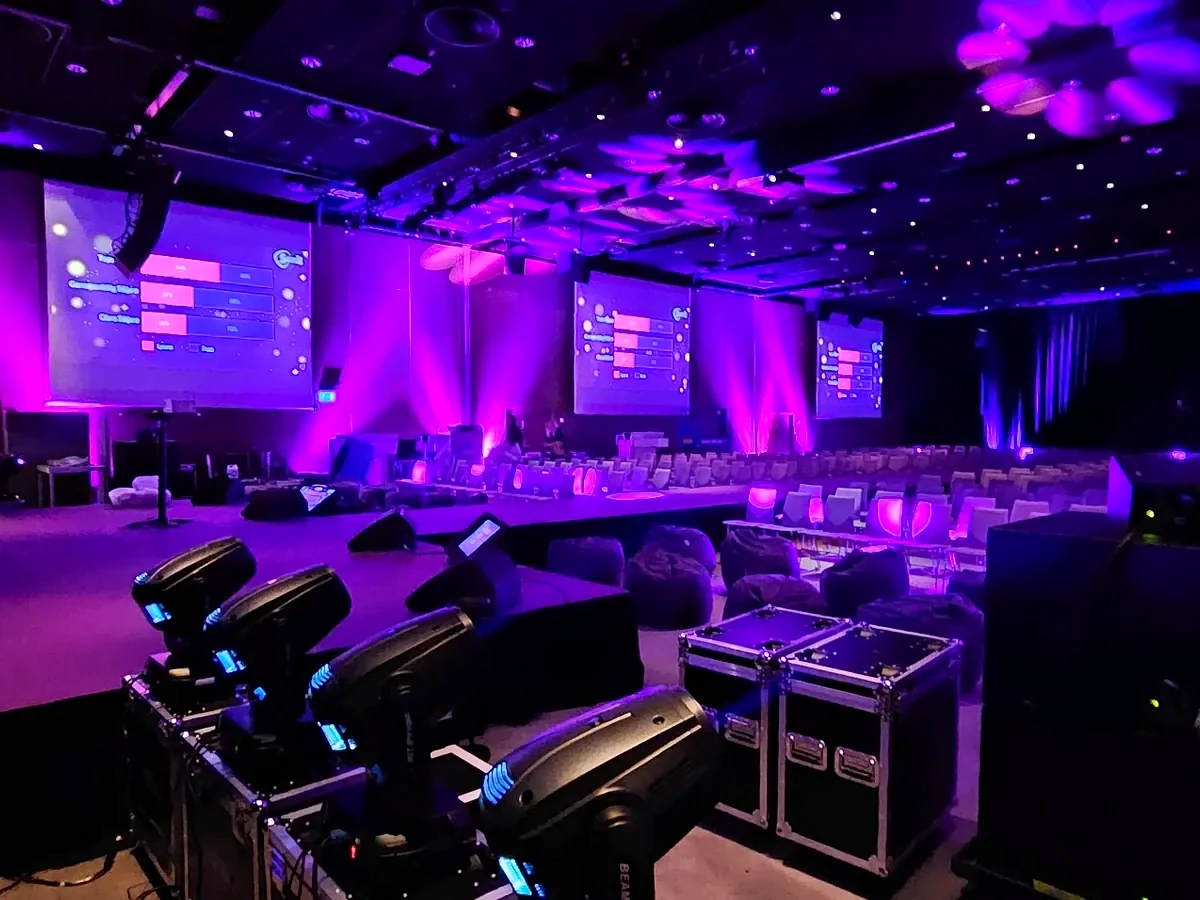 Större konferenssal med skärmar, scen och lila ljussättning